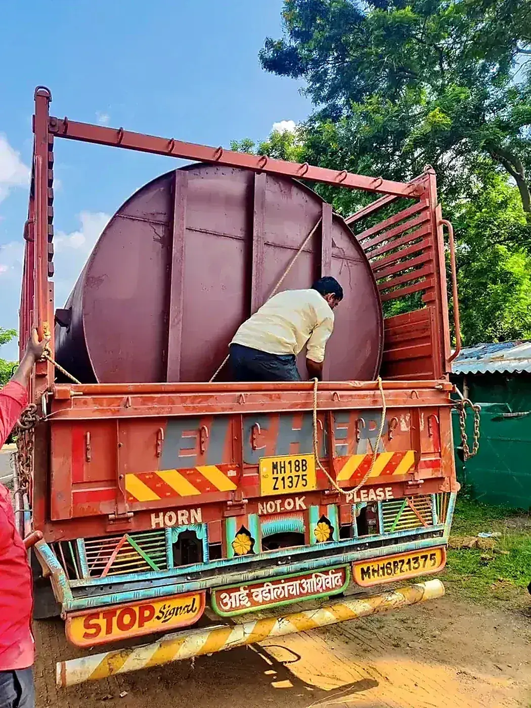 Tank loaded on Eicher truck — worker performing final securing check