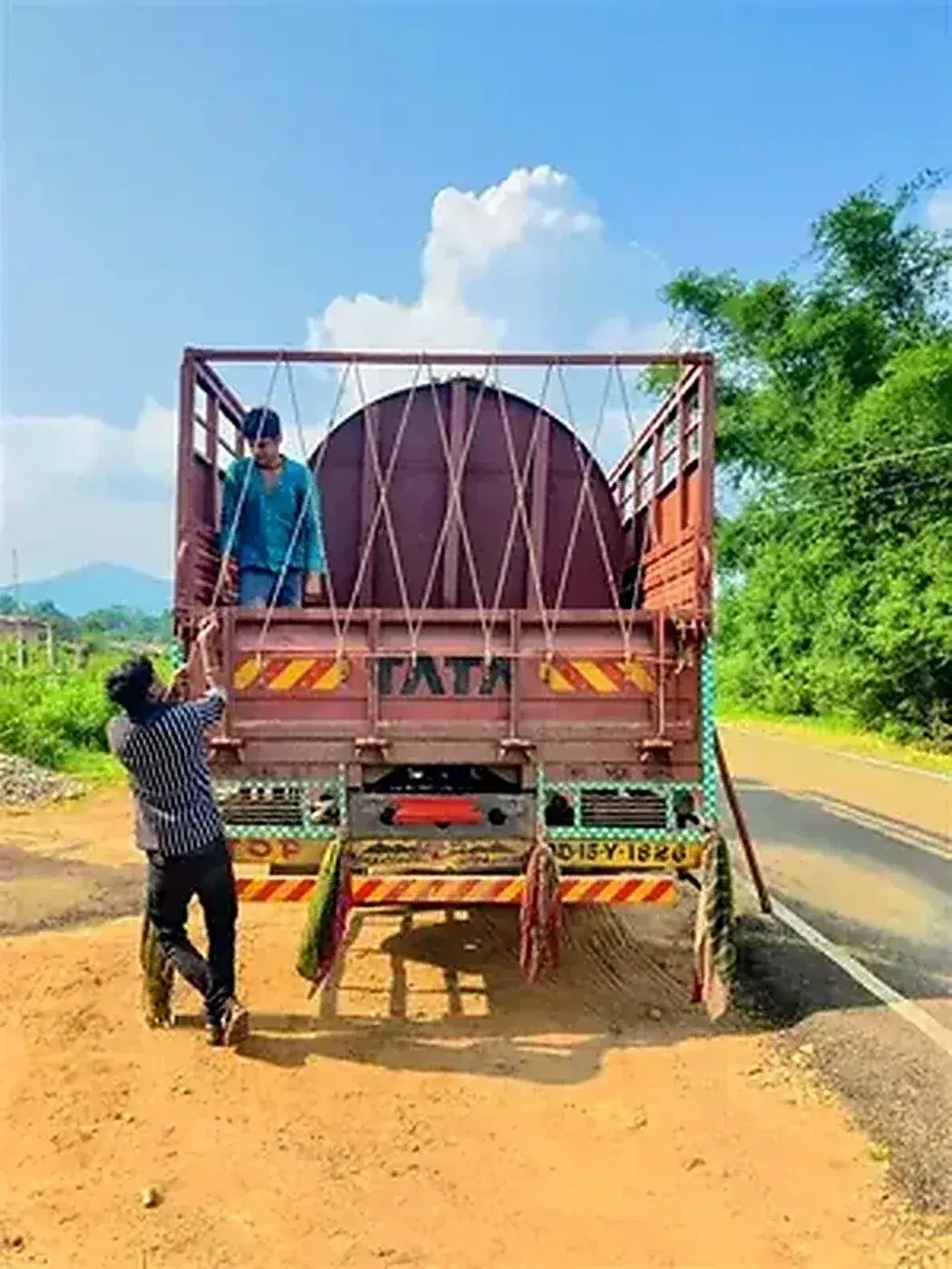 Tank loaded on Tata truck — hand-secured with criss-cross rope rigging